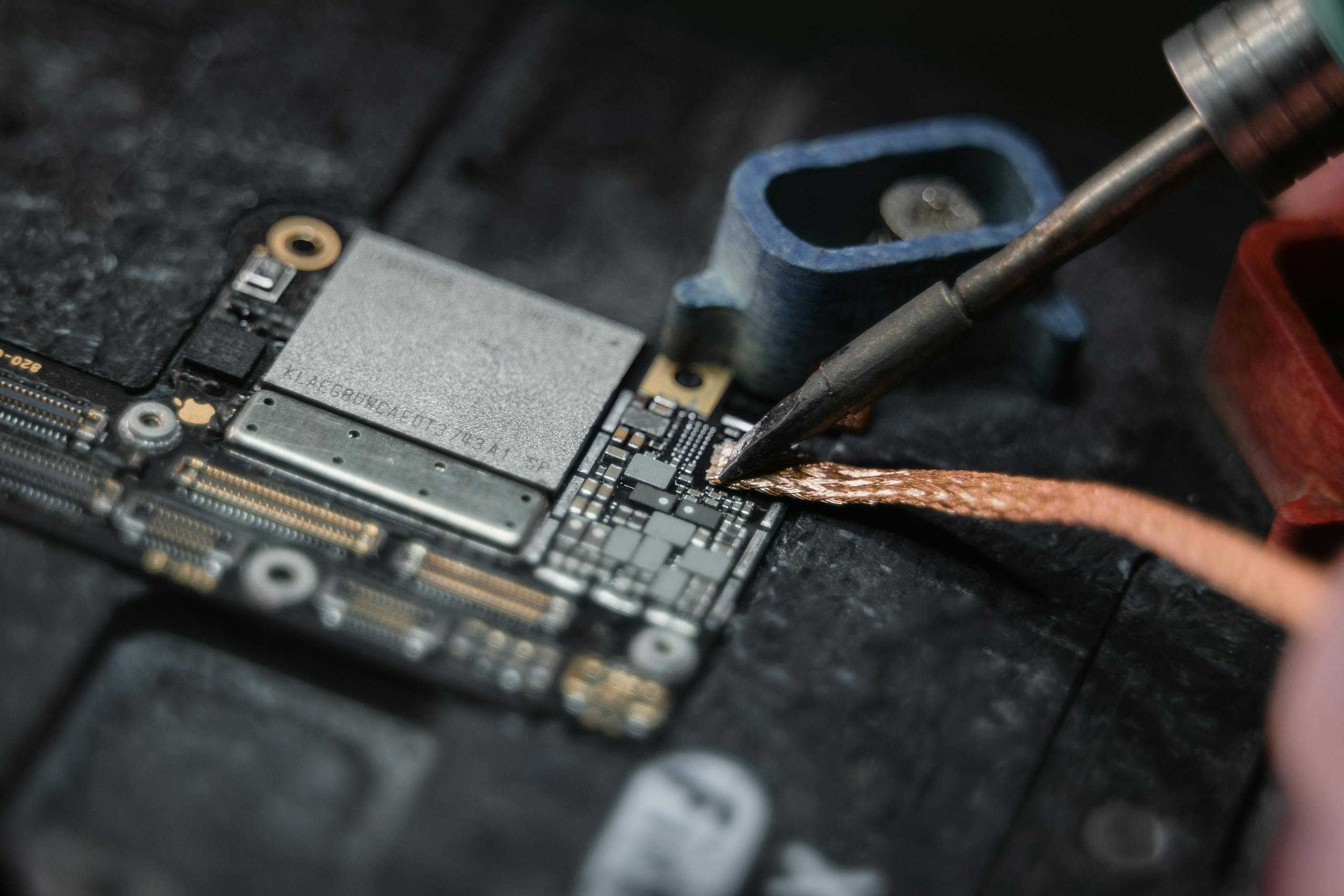 Detailed close-up of a soldering iron working on a circuit board, showcasing Ipad repair.